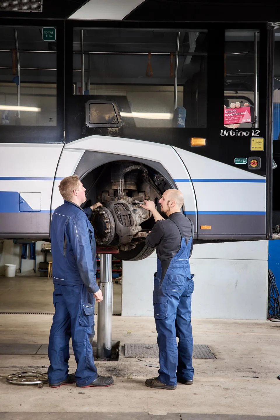 Mitarbeiter:innen reparieren und warten an einem der Busse